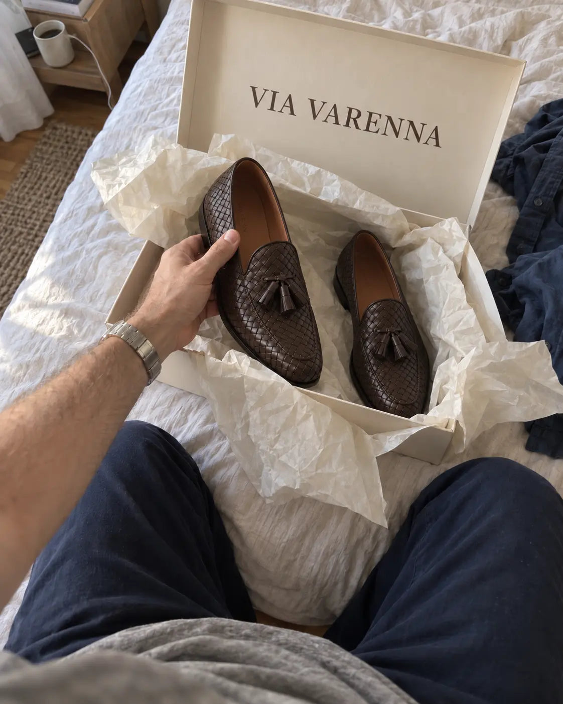 Cliente sosteniendo mocasines marrones trenzados junto a una caja VIA VARENNA